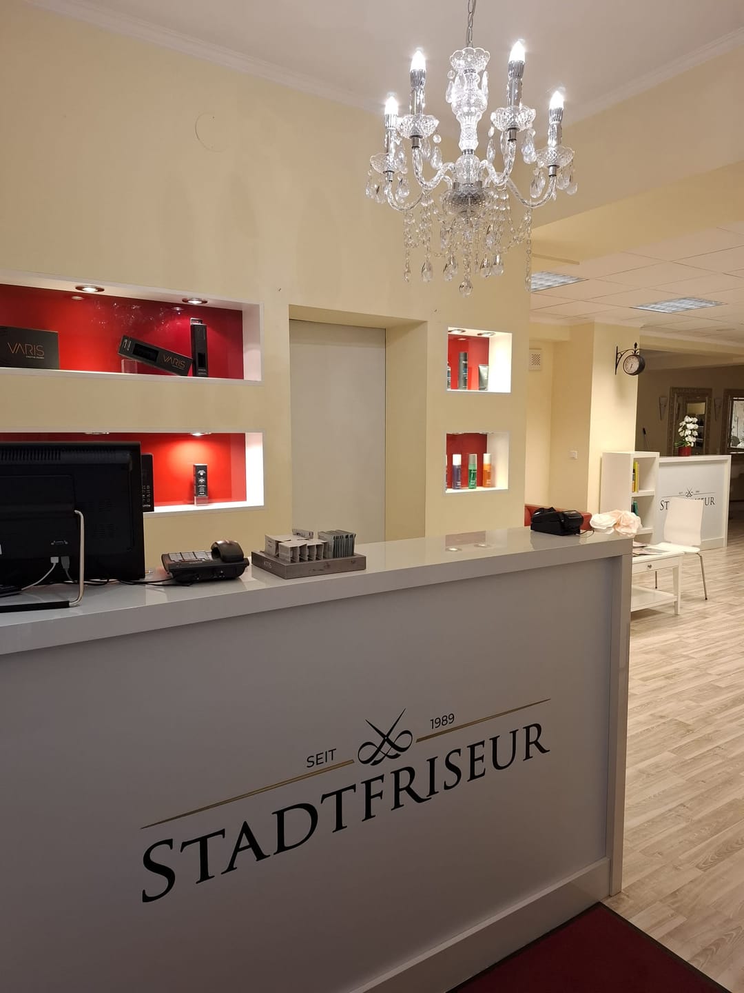 Der Empfangsbereich mit Kristallluster, roten Produktnischen und dem Logo auf dem Pult